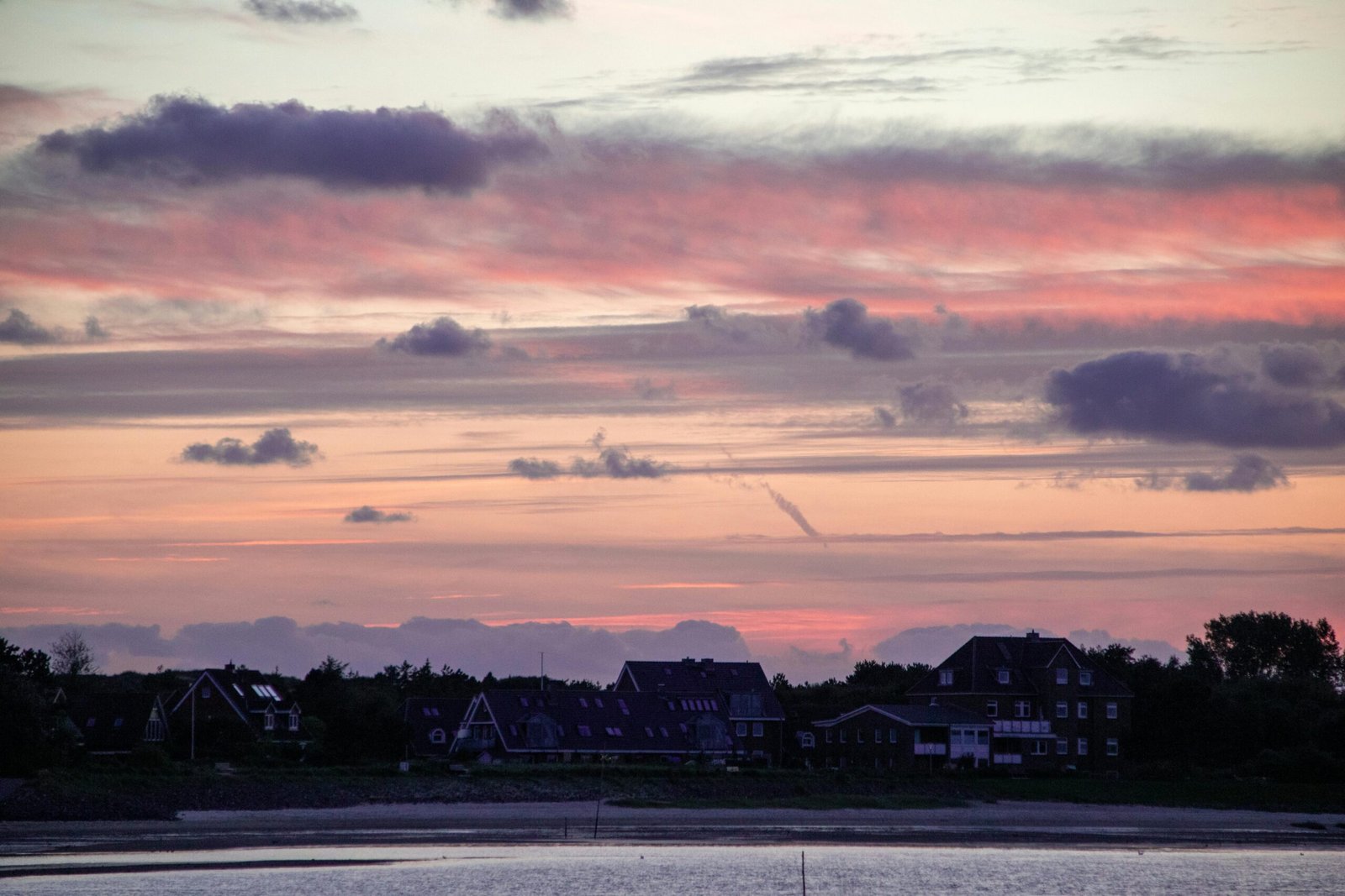 Beautiful sunset view of Wittdün, Amrum with colorful clouds over the North Sea shoreline.